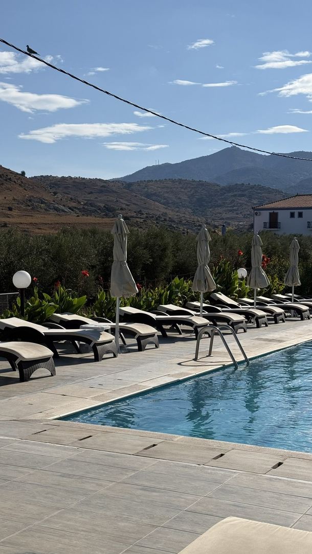 Basen z leżakami w hotelu Marilena na tle gór